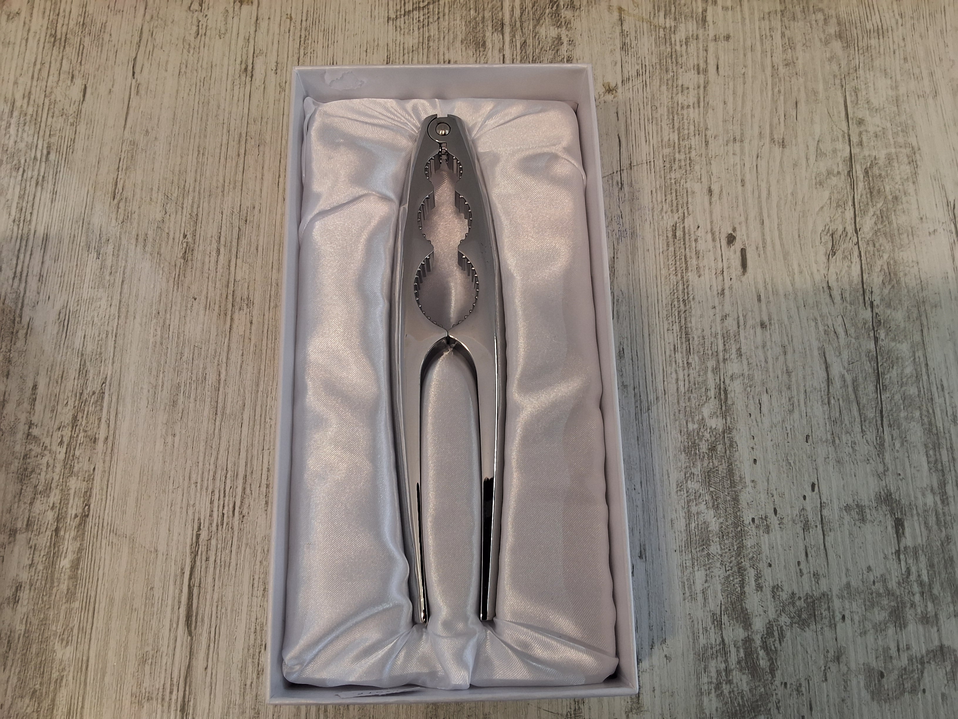 Schiaccianoci in acciaio.Mis.18×4.Con l'articolo è compresa la scatola bianca e il sacchetto cellophane porta confetti